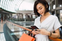Jeune belle asiatique femme avec sacs dans centre commercial — Photo de stock