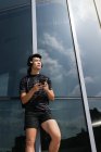 Щасливий азіатський спортивний чоловік використовує навушники та смартфон — стокове фото