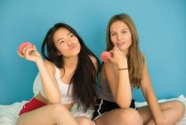 Deux jeunes femmes s'amusent avec des beignets — Photo de stock