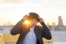 Jeune millénaire asiatique profiter du coucher de soleil dans les écouteurs — Photo de stock