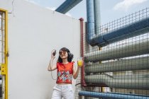 Mujer asiática con auriculares de pie contra la pared - foto de stock