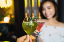 Vue rapprochée de deux cocktails dans les mains dans un bar confortable — Photo de stock