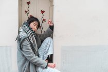 Junge erwachsene asiatische Frau sitzt auf Fensterbank mit Blumen — Stockfoto
