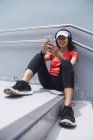 Jovem asiático mulher desportiva usando fones de ouvido e inteligente em escadas — Fotografia de Stock