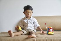 Bambino che gioca con i giocattoli sul divano — Foto stock