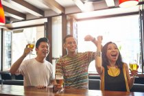 Young asian friends cheering together in bar — Stock Photo
