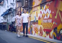 Junge attraktive asiatische Paar umarmen und zu Fuß auf der Straße — Stockfoto