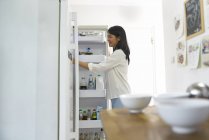 Heureux jeune asiatique femme regarder dans réfrigérateur — Photo de stock