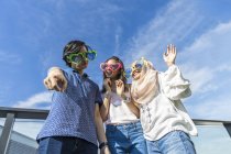 Gruppo di amici che indossano occhiali divertenti divertirsi contro il cielo blu — Foto stock