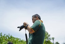Молодой фотограф рассматривает снимки на камеру — стоковое фото