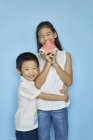 Happy asian siblings with watermelon against blue background — Stock Photo