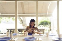 Jeune jolie asiatique femme en utilisant smartphone dans café — Photo de stock