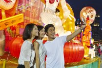 Three young asian friends having fun at chinese new year and taking selfie, Singapore — Stock Photo
