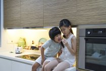 Frères et sœurs partageant un chignon dans la cuisine — Photo de stock
