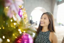 Молодая привлекательная азиатка рядом с елкой — стоковое фото