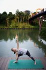 Young asian sporty woman making stretching near lake — Stock Photo