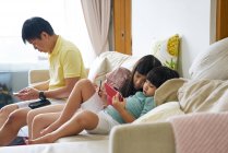 Щаслива молода азіатська сім'я разом використовує цифровий планшет вдома — стокове фото