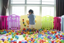 Rear view of baby having fun roaming around in a play pen — Stock Photo