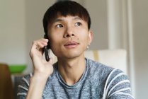 Young adult asian man using smartphone at home — Stock Photo