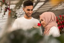 Молода мусульманська дівчина пахне трояндою в квітковому магазині — стокове фото