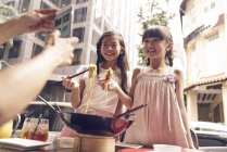 Felice famiglia asiatica mangiare tagliatelle insieme in strada caffè e scattare foto — Foto stock