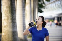 Giovane asiatica sportiva donna che beve acqua dalla bottiglia — Foto stock