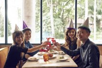 Happy young asian friends celebrating christmas together in cafe and cheering wine — Stock Photo