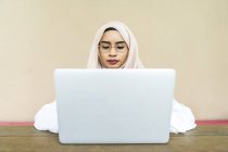 Jeune asiatique musulman femme en utilisant ordinateur portable à l'intérieur — Photo de stock
