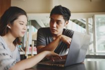 Giovane attraente asiatico coppia utilizzando laptop in caffè — Foto stock