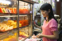 Asian woman looking out in food market — Stock Photo