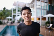 Young attractive asian man portrait against pool — Stock Photo