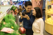 Joven atractivo asiático pareja juntos compras en mall en Navidad - foto de stock