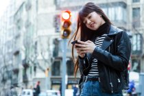 Junge langhaarige Frau geht und surft auf ihrem Smartphone — Stockfoto