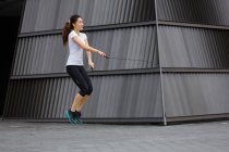 Une jeune femme asiatique fait de l'exercice avec saut à la corde, en plein air à Singapour . — Photo de stock