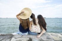 Rear view of Three young ladies chilling at the beach. — Stock Photo
