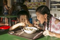 Deux heureux jeunes asiatiques enfants manger dans café — Photo de stock