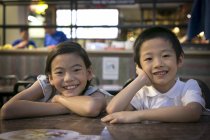 Dois feliz jovem asiático crianças olhando para câmera no café — Fotografia de Stock