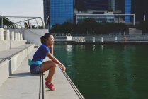 Вид сбоку на молодую спортивную женщину, сидящую на ступеньках — стоковое фото