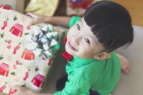 A happy little boy in a green shirt opens his Christmas present — Stock Photo