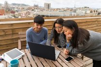 Jeunes asiatiques travaillant ensemble avec ordinateur portable sur le balcon — Photo de stock