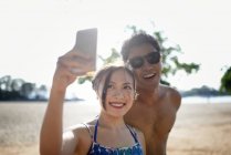 Young attractive asian couple taking selfie on smartphone — Stock Photo