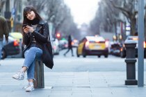 Молода приваблива азіатська жінка в місті за допомогою смартфона — стокове фото