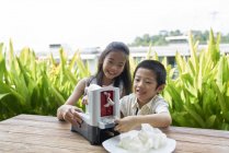 Счастливые азиатские братья и сестры делают рисовые чипсы вместе — стоковое фото