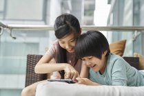 Щаслива молода азіатська сім'я разом, діти використовують цифровий планшет вдома — стокове фото