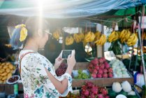 COMMUNIQUÉS Jeune femme prenant des photos d'un étal de fruits de la rue à Koh Chang, Thaïlande — Photo de stock