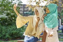 Beautiful women in a tudung taking selfies at the park in Singapore — Stock Photo