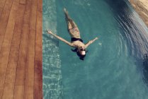 Schöne junge Frau schwimmt auf dem Rücken im Pool — Stockfoto
