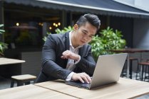 Joven asiático exitoso hombre de negocios usando laptop - foto de stock