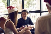 Felici giovani amici asiatici che celebrano il Natale insieme nel caffè e condividono regali — Foto stock