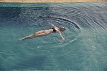Bella giovane donna nuotare sul retro in piscina — Foto stock